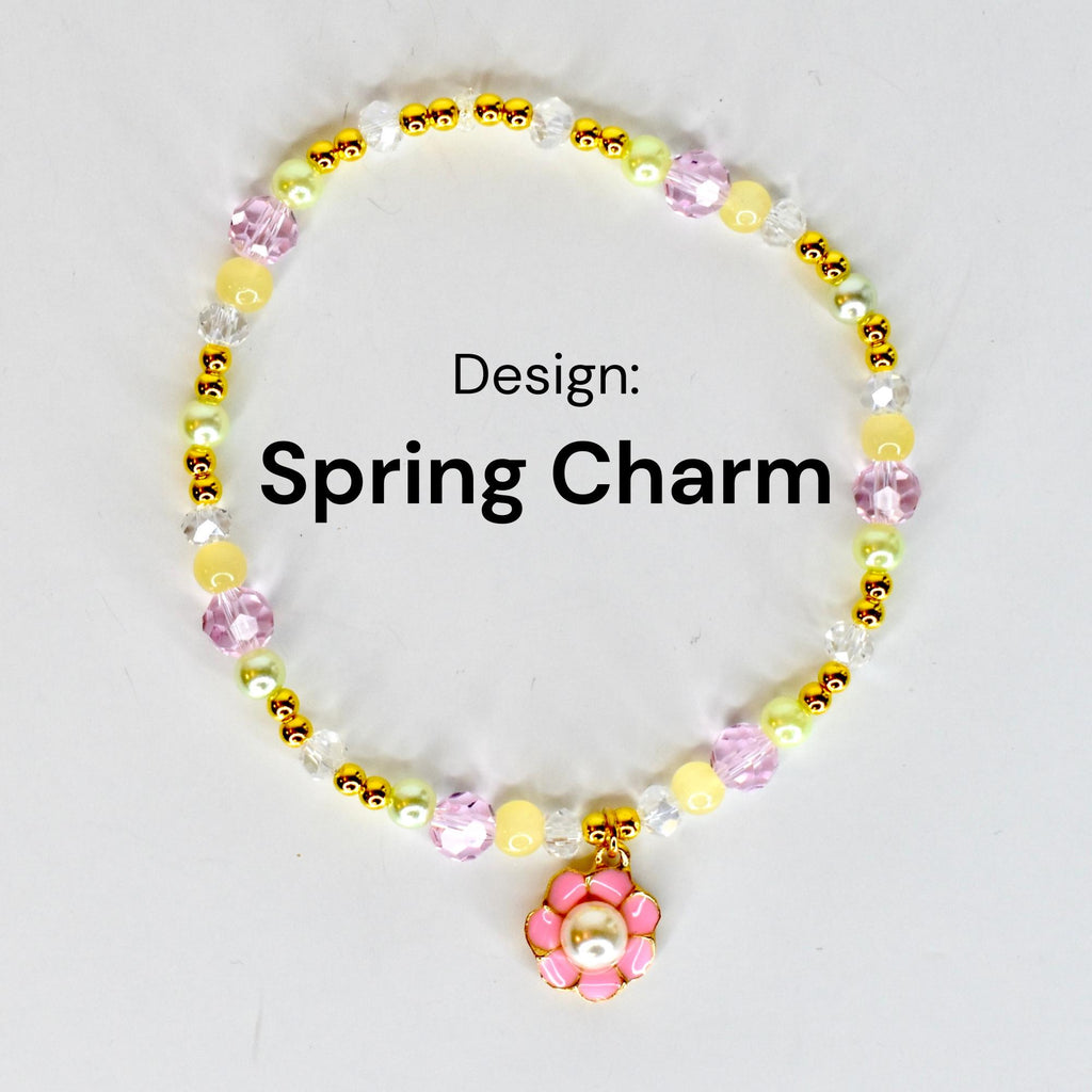 A beaded bracelet with the text "Spring Charm." The bracelet features a variety of beads in yellow, pink, clear, and gold colors. A pink flower charm with a pearl center hangs from the bracelet.
