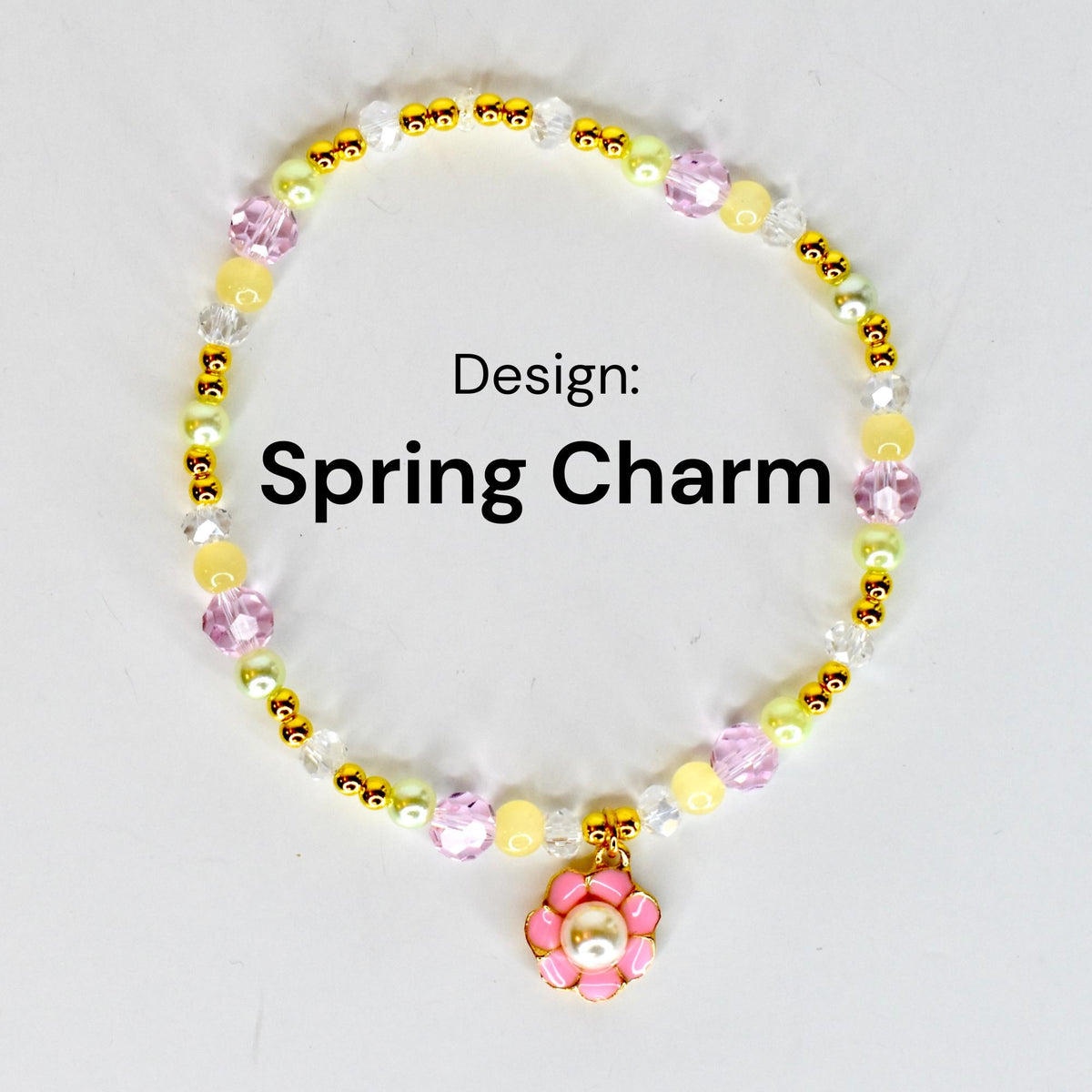 A beaded bracelet with the text "Spring Charm." The bracelet features a variety of beads in yellow, pink, clear, and gold colors. A pink flower charm with a pearl center hangs from the bracelet.