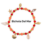 A beaded bracelet with red and orange beads, gold accents, and seashell charms. The bracelet features a starfish, various seashells, and the text "Bichota Del Mar".