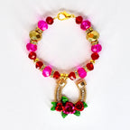 A beaded tumbler handle bracelet with a gold clasp, featuring pink, red, and gold beads. The handle bracelet has a gold horseshoe pendant adorned with rhinestones and a cluster of red roses with green leaves.