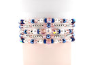 Stack of beaded bracelets with pink, white, silver, and blue beads. The bracelets feature a mix of pearl, crystal, and metallic beads. The bracelets are stacked on top of each other.