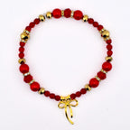 A red beaded bracelet with gold accents and a gold bow charm. The bracelet features a mix of red beads, including round and faceted shapes, interspersed with gold-colored beads and small crystal accents. The gold bow charm hangs at the bottom.