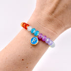 A beaded bracelet with a rainbow color scheme. The bracelet features a gold charm with a blue enamel background and the letter "F". The beads are various colors, including red, orange, white, blue, purple, and yellow.