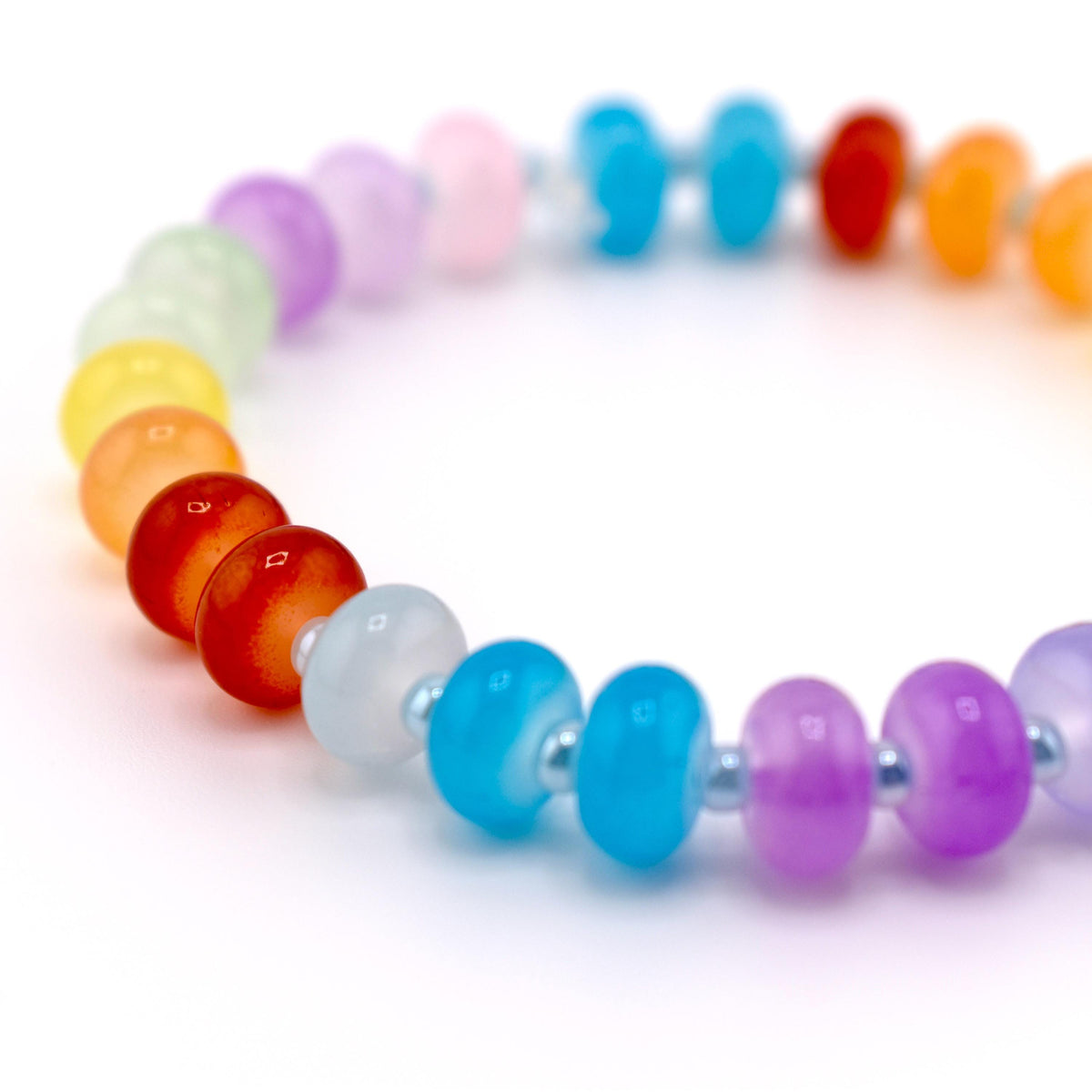 A rainbow-colored beaded bracelet. The bracelet features a variety of colors, including red, orange, yellow, green, blue, and purple. The beads are round and appear to be made of glass or a similar material. The bracelet is on a white background.