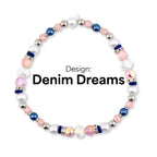A beaded bracelet with the text "Denim Dreams." The bracelet features a mix of white, pink, blue, and iridescent beads. Silver-colored beads and dark blue accents are also present in the design.