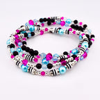 A set of four beaded bracelets in a spiral arrangement. The bracelets feature a mix of black, pink, light blue, and clear beads, along with silver and black striped accents. The beads are strung on a silver wire.