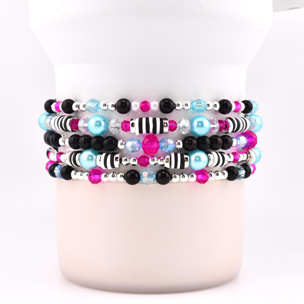 Stack of five beaded bracelets with a variety of beads. The bracelets feature black, silver, pink, light blue, and clear beads. Some bracelets have black and white striped beads.