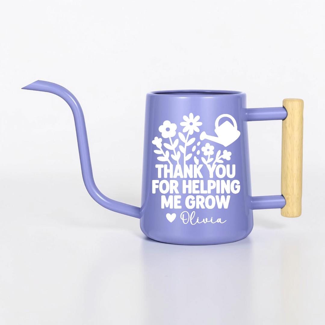 A periwinkle watering can with a long, curved spout and a wooden handle. The can features a white floral design and the text "THANK YOU FOR HELPING ME GROW" with a heart and the name "Olivia".