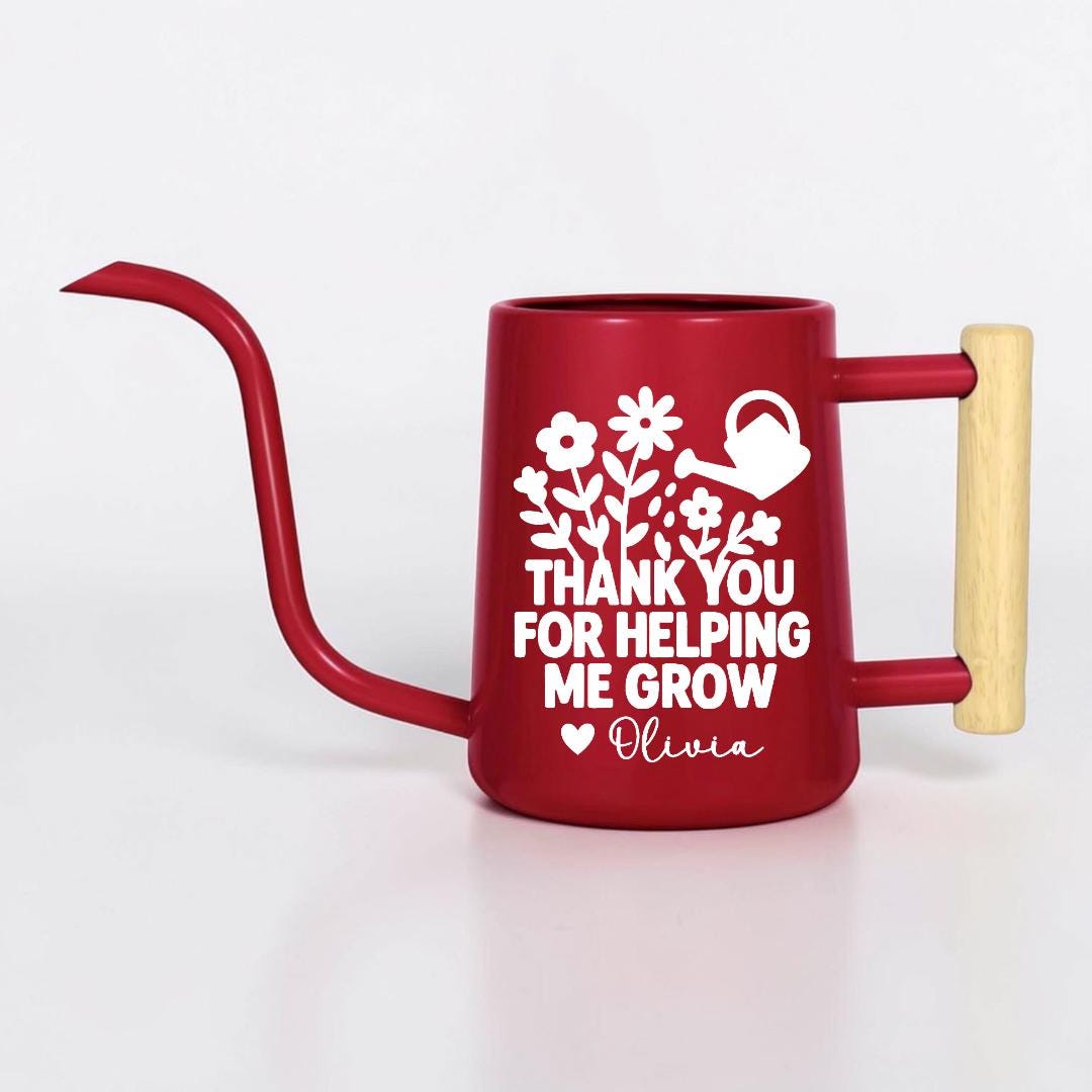 Red watering can with a long, curved spout and a wooden handle. The can features a white floral design and the text "THANK YOU FOR HELPING ME GROW" with the name "Olivia"