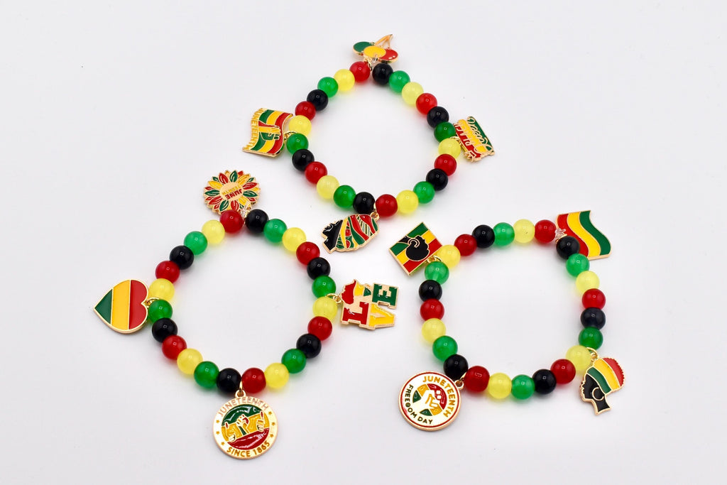 Three beaded bracelets with red, yellow, green, and black beads. Each bracelet features Juneteenth-themed charms, including flags, a heart, and a medallion with text. The bracelets are displayed on a white surface.