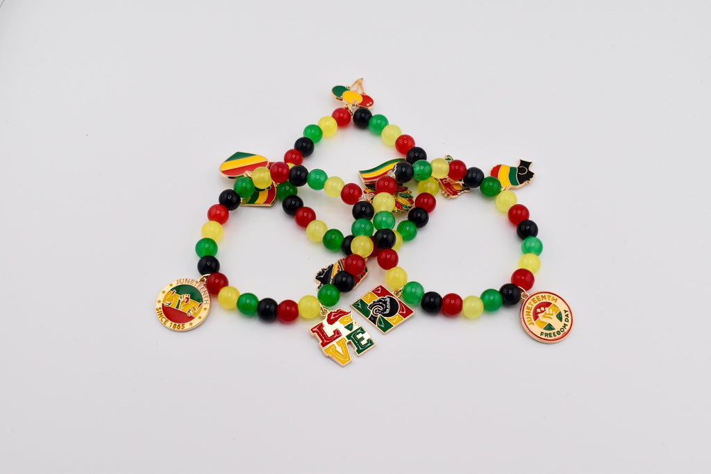 Three beaded bracelets with red, yellow, green, and black beads. Each bracelet has charms with flags, the word "LOVE", and a round charm with text. The bracelets are on a white background.