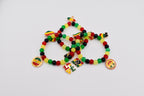 Three beaded bracelets with red, yellow, green, and black beads. Each bracelet has charms with flags, the word "LOVE", and a round charm with text. The bracelets are on a white background.