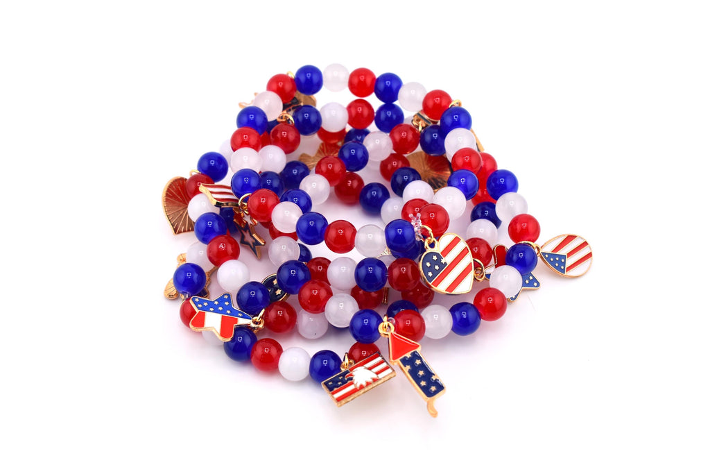 A collection of beaded bracelets in red, white, and blue. The bracelets feature round beads and charms with American flag designs. The charms include hearts, stars, and flag shapes, perfect for patriotic celebrations.