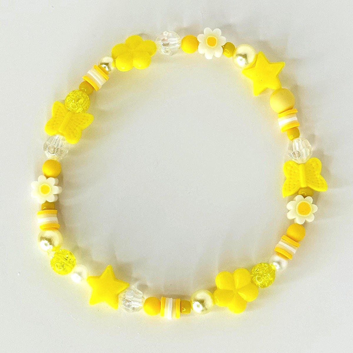 A beaded bracelet featuring yellow star, butterfly, and flower charms. The bracelet includes white and yellow beads, with clear spacer beads. The bracelet is on a white background.