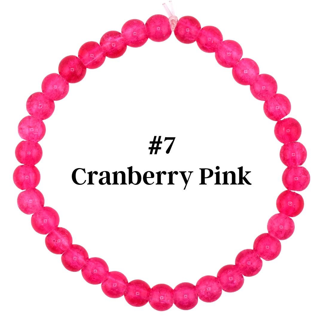 A cranberry pink beaded bracelet. The bracelet is made of round, polished beads in a vibrant shade of pink. The text "#7 Cranberry Pink" is displayed in black font within the bracelet's center. The beads are strung together on a clear elastic cord.