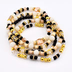 A collection of beaded waist beads in various colors. The beads include black, white, gold, peach, and clear. The beads are strung together to create a decorative accessory.
