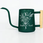 A dark green watering can with a long, slender spout and a light-colored wooden handle. The body features a white line-art illustration of a floral bouquet and the text Custom Text printed in a cursive font on the front surface.