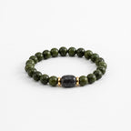 Handmade beaded bracelet with dark green beads and one black stone bead in the center with two gold spacer beads on either side.