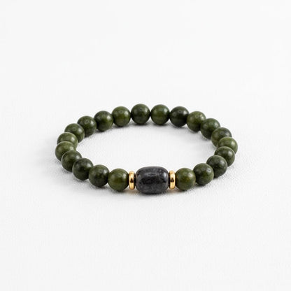 Handmade beaded bracelet with dark green beads and one black stone bead in the center with two gold spacer beads on either side.
