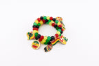 A beaded bracelet with red, yellow, green, and black beads. The bracelet has several charms, including a round charm with text and a flag-shaped charm. The bracelet is on a white background.
