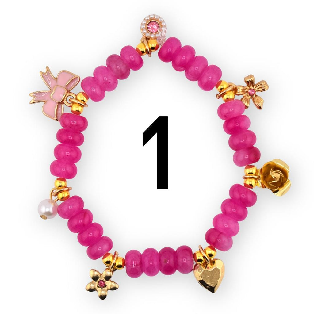 A pink beaded bracelet with gold-colored charms, including a bow, flowers, a heart, and a pearl. The bracelet has the number 1 in black in the center.