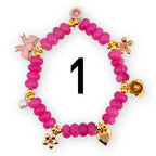 A pink beaded bracelet with gold-colored charms, including a bow, flowers, a heart, and a pearl. The bracelet has the number 1 in black in the center.