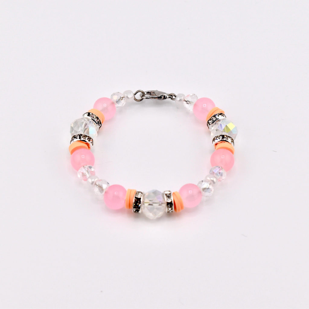 A beaded bracelet featuring pink and clear beads, accented with orange spacers and sparkling crystal elements. The bracelet is secured with a silver-tone clasp, showcasing a delicate and feminine design.