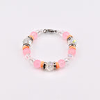 A beaded bracelet featuring pink and clear beads, accented with orange spacers and sparkling crystal elements. The bracelet is secured with a silver-tone clasp, showcasing a delicate and feminine design.