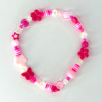 A pink beaded bracelet featuring a variety of beads, including flower and butterfly shapes, star, and round beads. The bracelet has a mix of pink shades, white, and clear beads.