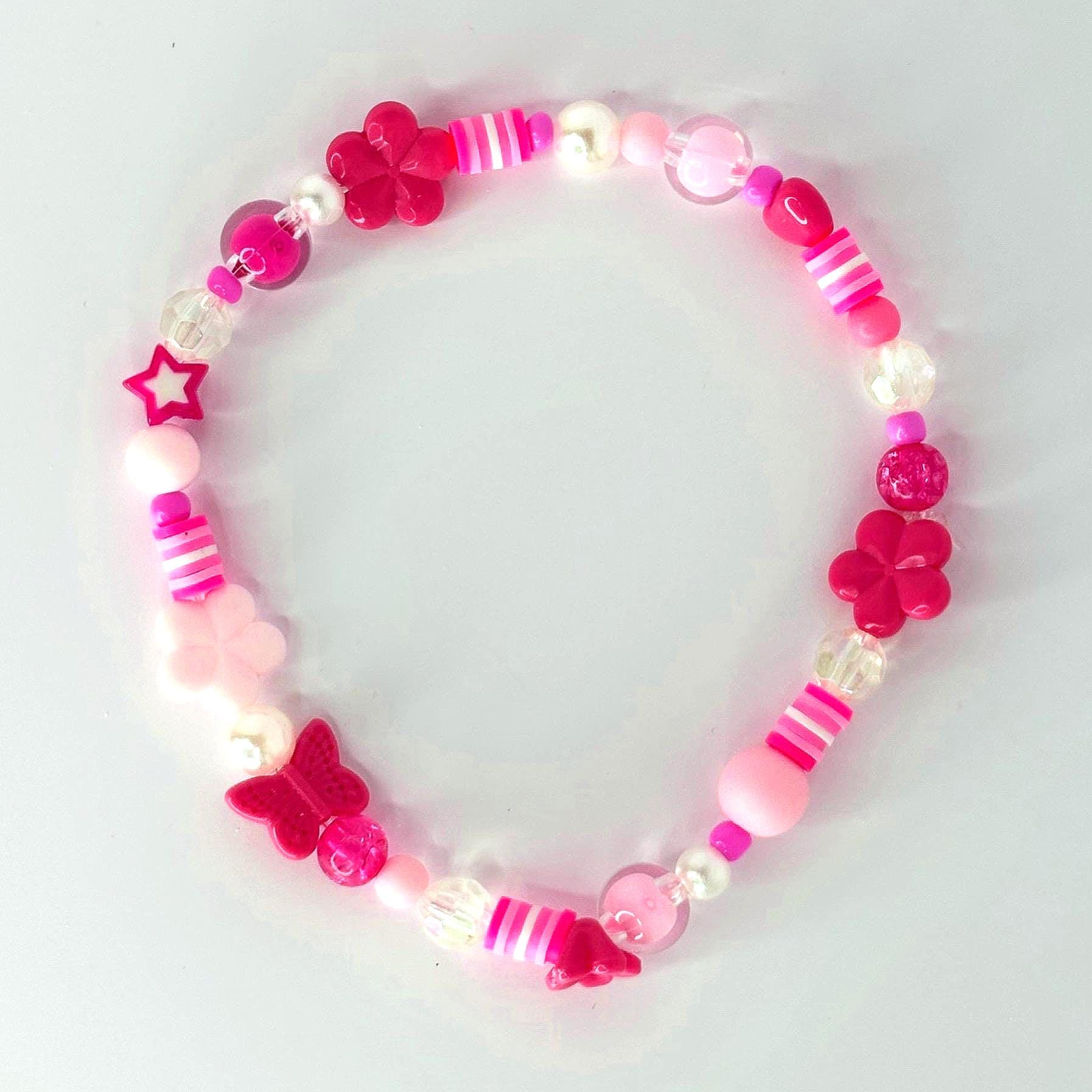 A pink beaded bracelet featuring a variety of beads, including flower and butterfly shapes, star, and round beads. The bracelet has a mix of pink shades, white, and clear beads.