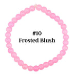 A light pink beaded bracelet with the text "#10 Frosted Blush". The bracelet is made of small, round beads strung together. The beads are a soft, pastel pink color.