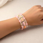 A multi-strand bracelet featuring a mix of beads in shades of pink, peach, and clear. The bracelet includes round and disc-shaped beads, with silver-toned accents. The bracelet is wrapped around a wrist.