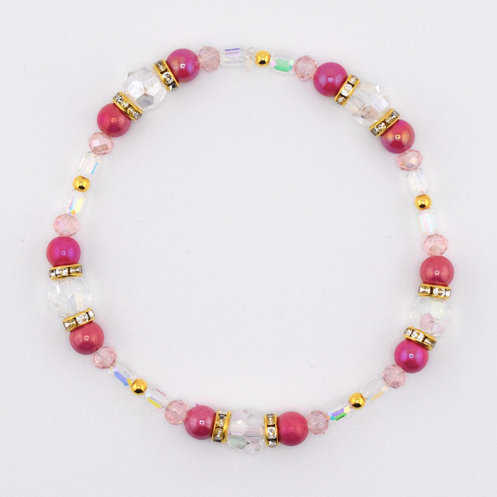 A beaded bracelet featuring alternating fuchsia and clear beads. The bracelet includes gold-colored spacers and accents. The beads are strung on a clear elastic cord, creating a delicate and elegant accessory.