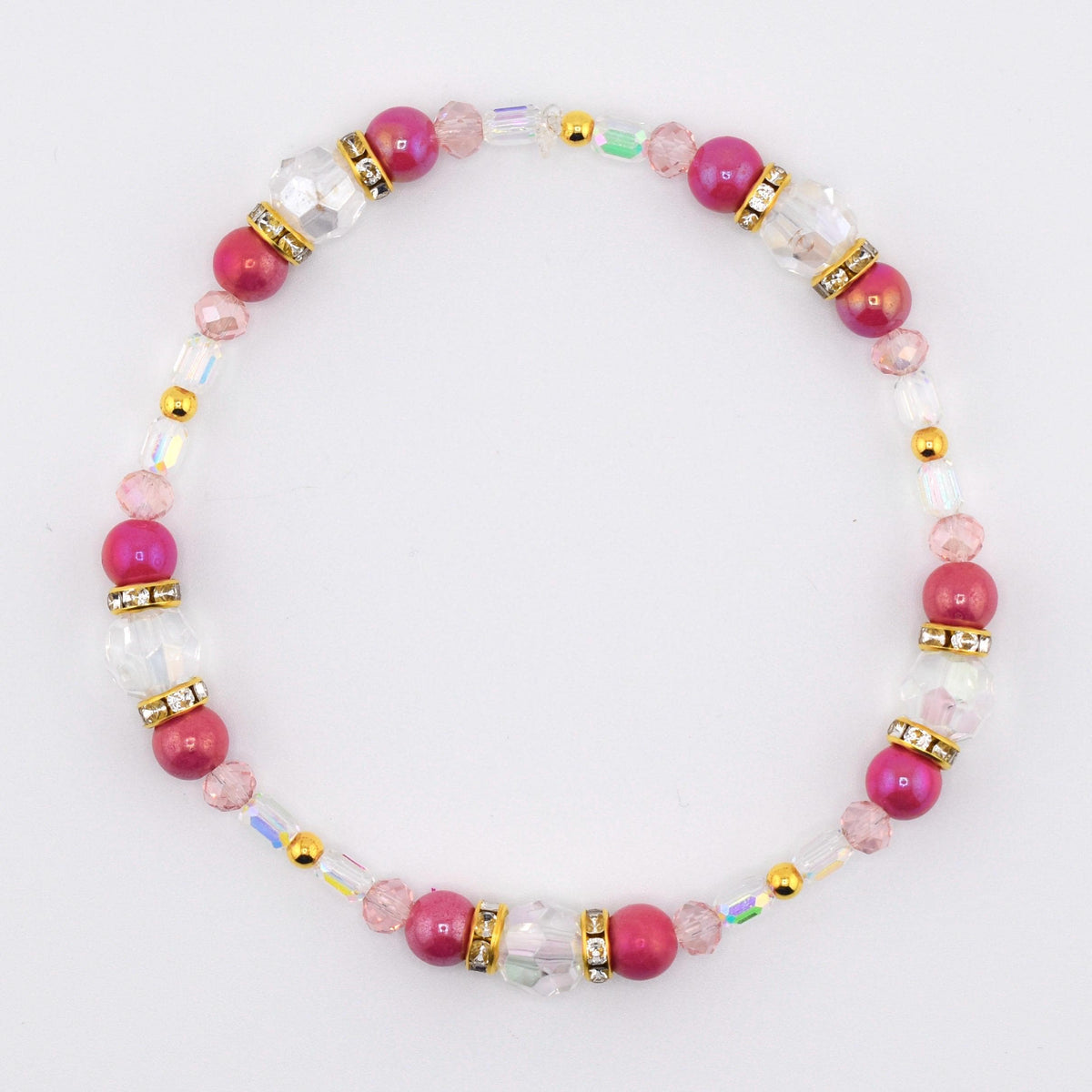 A beaded bracelet featuring alternating fuchsia and clear beads. The bracelet includes gold-colored spacers and accents. The beads are strung on a clear elastic cord, creating a delicate and elegant accessory.