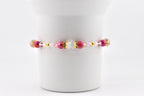 A beaded bracelet featuring a combination of pink, gold, and clear beads. The bracelet has a central section with a large clear bead and smaller pink beads, with gold accents and smaller pink and clear beads on either side.