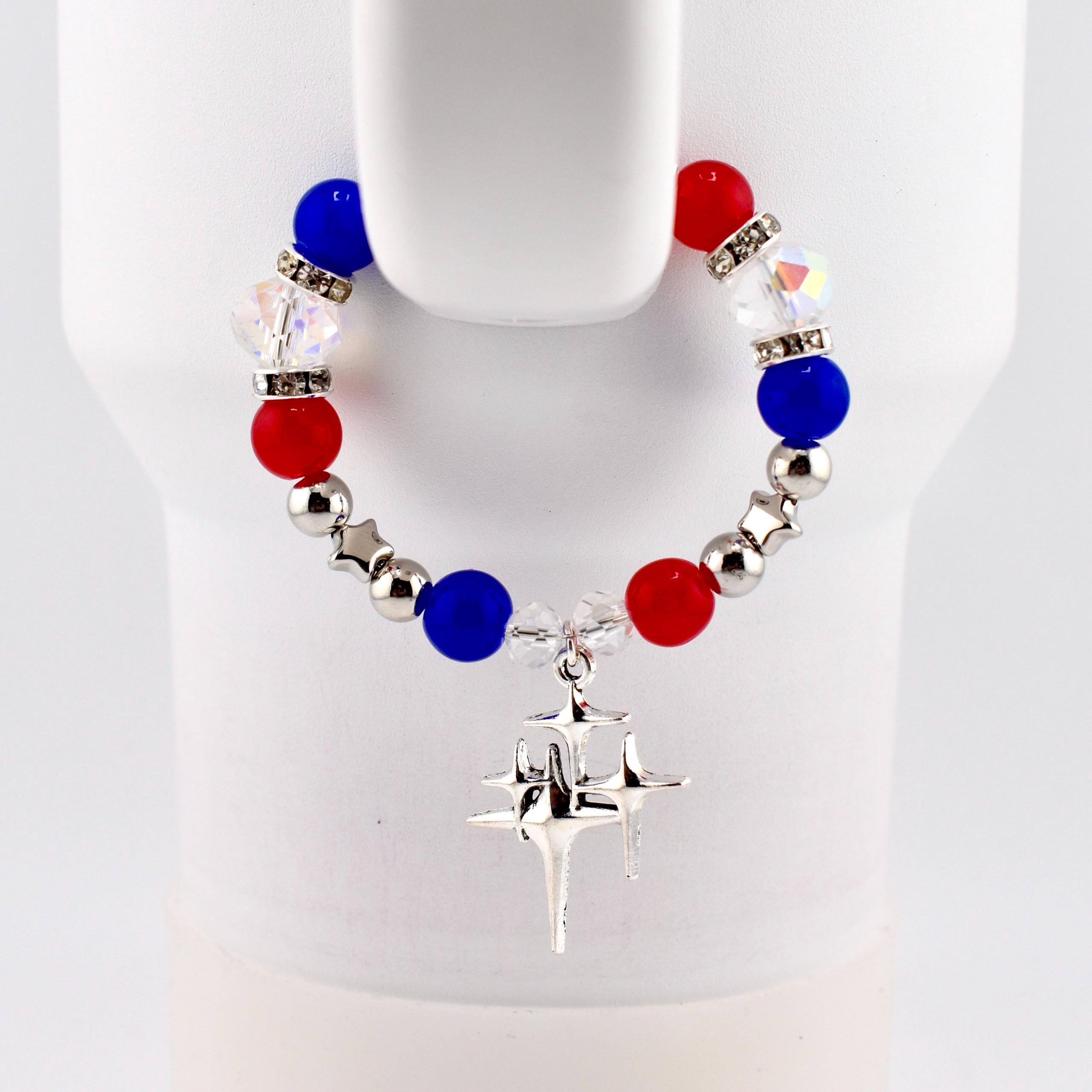 A patriotic tumbler handle bracelet featuring red, white, and blue beads with silver accents. The tumbler bracelet includes a dangling silver star charm. The beads are interspersed with clear, faceted beads. The bracelet is displayed against a white background.
