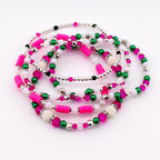 A collection of beaded bracelets in shades of pink, green, white, and silver. The bracelets feature a variety of bead sizes and shapes, including small round beads, cylindrical beads, and larger decorative beads. The bracelets are arranged in a circular pattern.