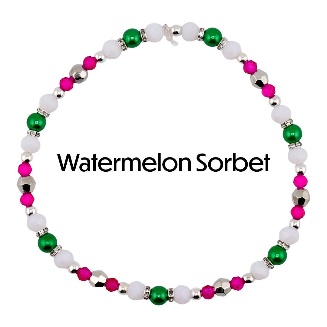A beaded necklace with the text "Watermelon Sorbet". The necklace features white, green, pink, and silver beads. The beads are arranged in a circular pattern, creating a bracelet or anklet.