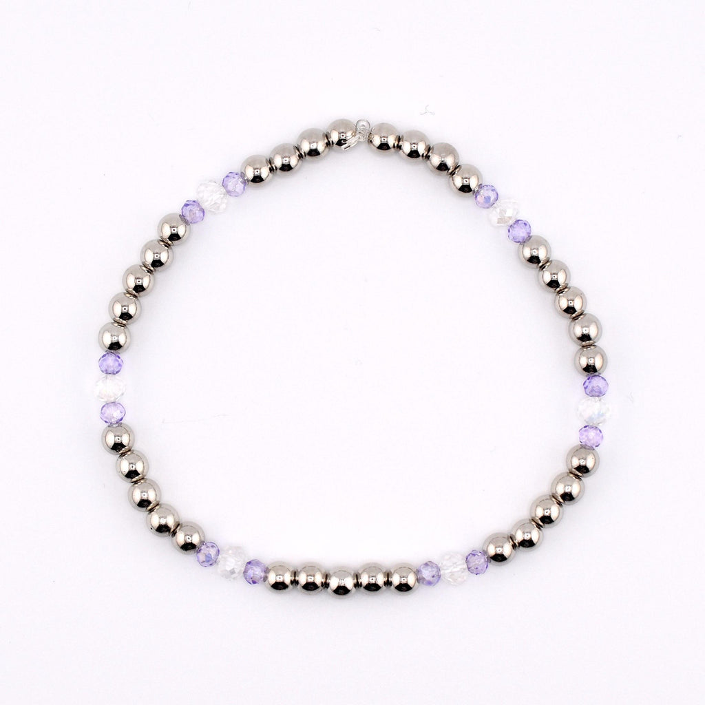 A silver beaded bracelet with alternating sections of silver beads, clear beads, and light purple beads. The bracelet is strung together and is displayed on a white background. The bracelet is a piece of jewelry.