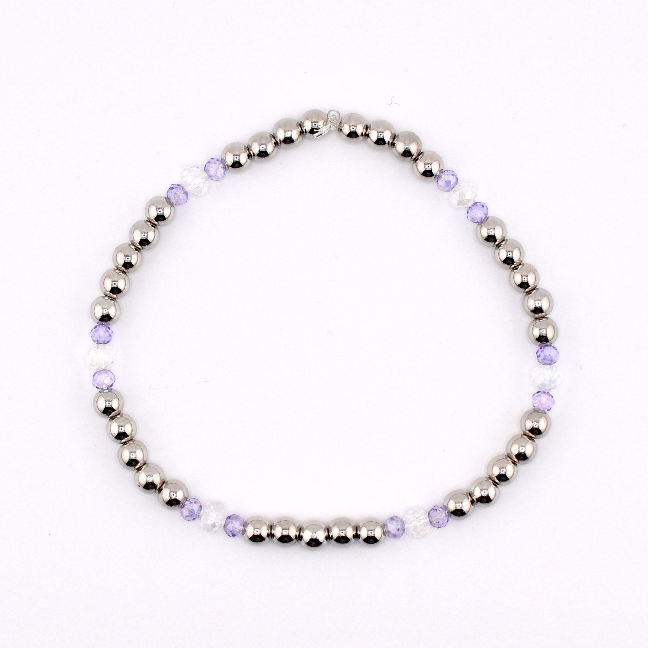 A silver beaded bracelet with alternating sections of silver beads, clear beads, and light purple beads. The bracelet is strung together and is displayed on a white background. The bracelet is a piece of jewelry.