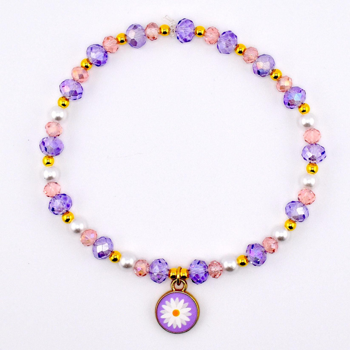 A beaded necklace featuring a daisy pendant. The necklace is composed of purple, pink, and white beads, interspersed with gold-colored accents. The pendant is a small, round charm with a white daisy on a purple background.