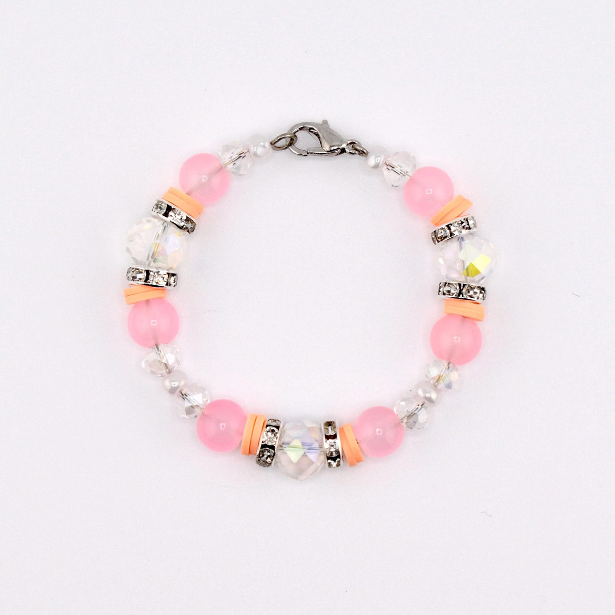 A delicate bracelet featuring pink and clear beads, accented with silver-toned spacers and orange-colored cylindrical beads. The bracelet is secured with a silver clasp. The beads are strung together, creating a circular design.