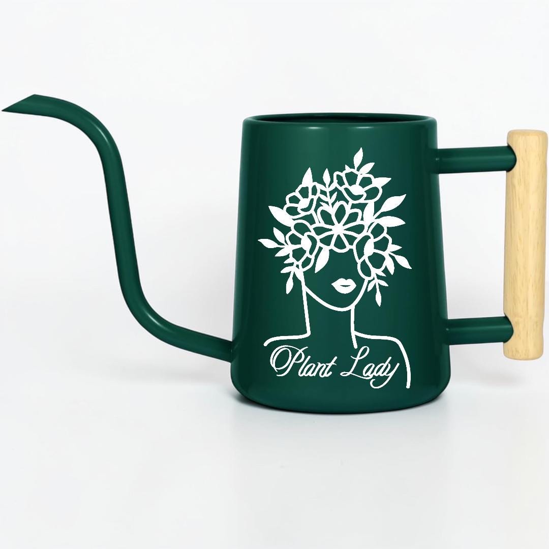 A dark green watering can with a long spout and a wooden handle. The can features a white graphic of a woman's face with a floral crown and the text "Plant Lady".