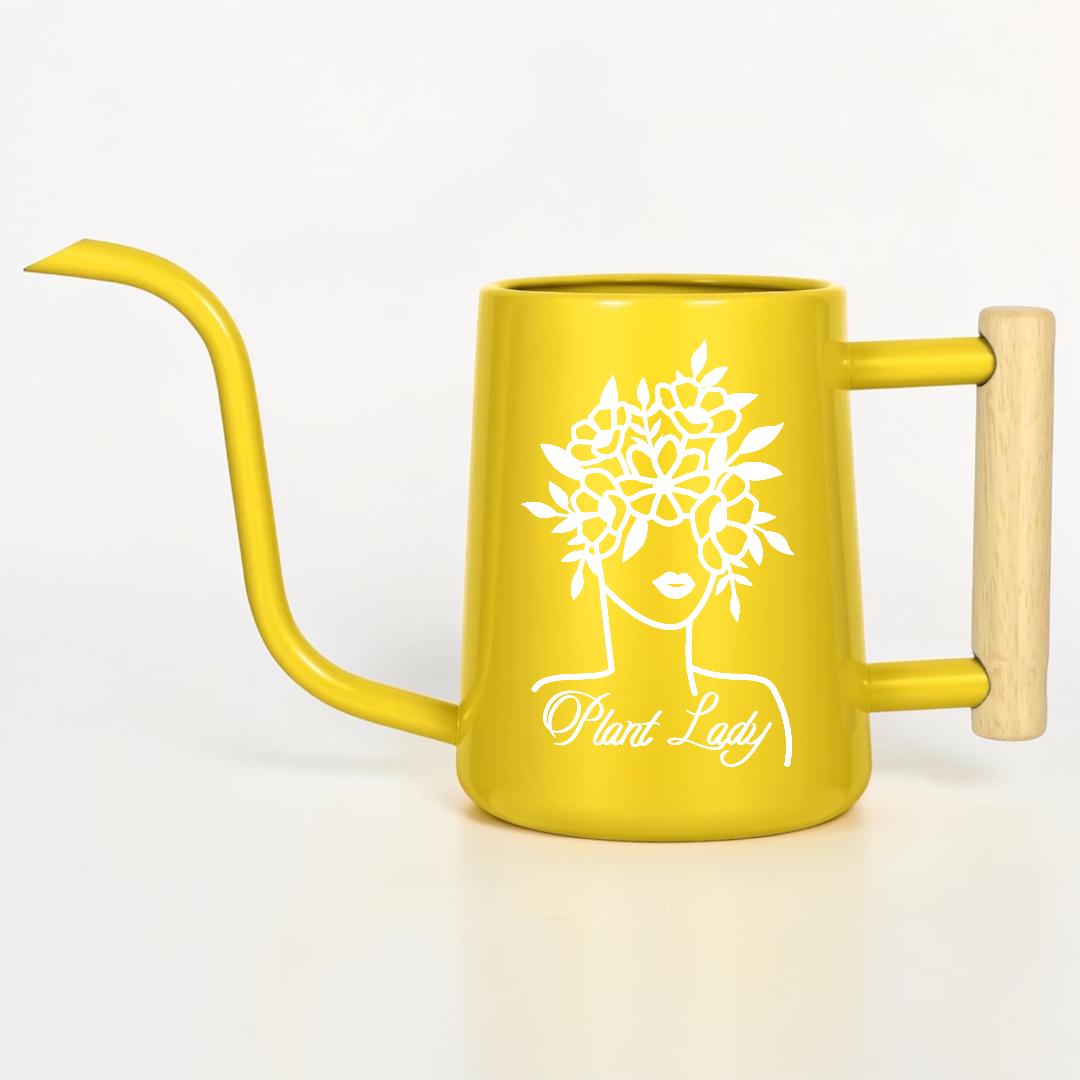 A yellow watering can with a long spout and wooden handle. The can features a white graphic of a woman's face with a floral crown and the words "Plant Lady". The watering can is designed for indoor or outdoor plant care.