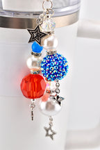 A patriotic-themed charm with red, white, and blue beads and star accents. The charm features a faceted red bead, a blue rhinestone-covered bead, and pearl-like beads, all connected with silver-toned chains and star charms.