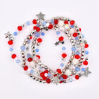 A collection of beaded necklaces with red, white, silver, and blue beads. The necklaces feature star-shaped charms and are arranged in a layered design. The beads are a mix of round and faceted shapes.