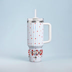 A white tumbler with a handle, a lid, and a straw. The tumbler has a pattern of blue vertical stripes and red stars. A decorative beaded bracelet with red, white, and blue beads and star charms is wrapped around the base.