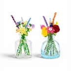 Two clear glass bottles containing artificial floral arrangements made from colorful beads. Each bouquet features various flower shapes in yellow, red, pink, and purple, with green beaded stems extending into the bottles.