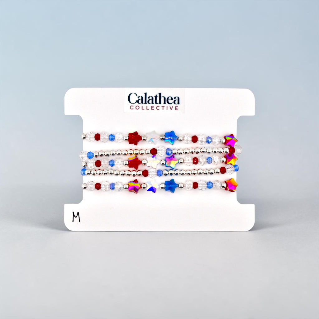 A set of beaded bracelets on a white card. The bracelets feature red, white, and blue beads, along with star-shaped beads in various colors.