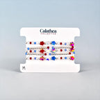 A set of beaded bracelets on a white card. The bracelets feature red, white, and blue beads, along with star-shaped beads in various colors.